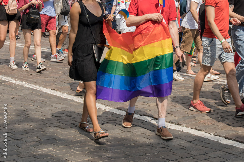 GayPride spectators with rainbow flag during Pride parade. Rainbow colors cloth
