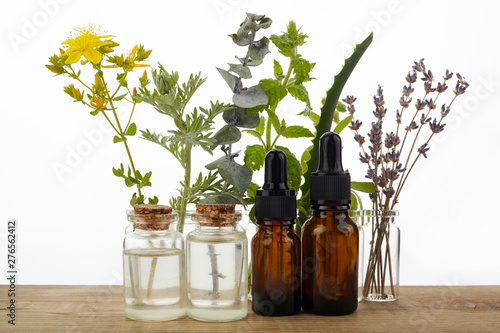 Essential oils with herbs and flowers on wooden table