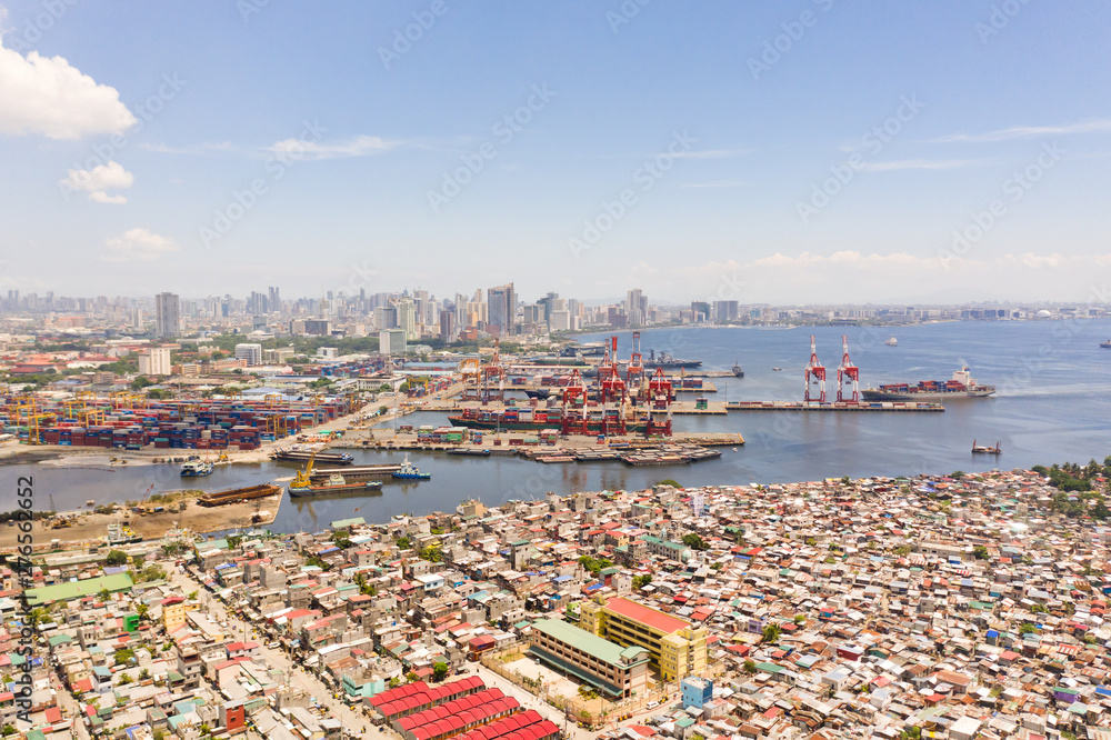 Obraz premium Port in Manila, Philippines. Sea port with cargo cranes. Cityscape with poor areas and business center in the distance, view from above. Asian metropolis.