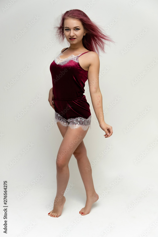 Concept portrait of a full-length pretty sexy girl with purple hair in beautiful red lingerie on a white background. She smiles, happy with life, happy. Hair flying, front view. Made in a studio. Concept portrait of a full-length pretty sexy girl with purple hair in beautiful red lingerie on a white background. She smiles, happy with life, happy. Hair flying, front view. Made in a studio.