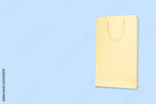Free Download Light Yellow color shopping paper bag on blue background with copy space. - GFXLoad