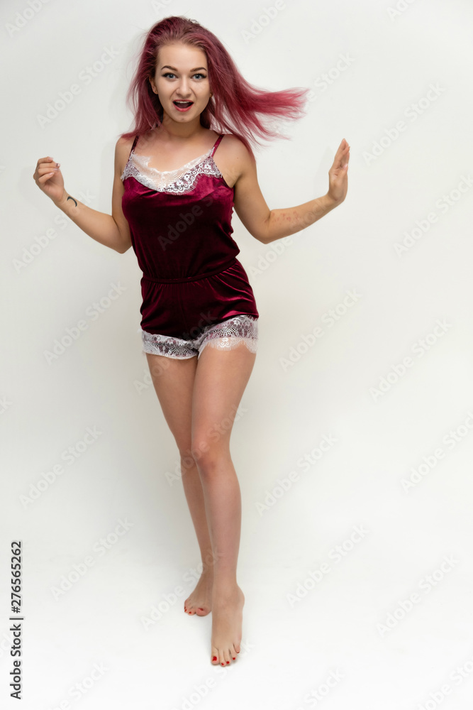 Concept portrait of a full-length pretty sexy girl with purple hair in beautiful red lingerie on a white background. She smiles, happy with life, happy. Hair flying, front view. Made in a studio. Concept portrait of a full-length pretty sexy girl with purple hair in beautiful red lingerie on a white background. She smiles, happy with life, happy. Hair flying, front view. Made in a studio.