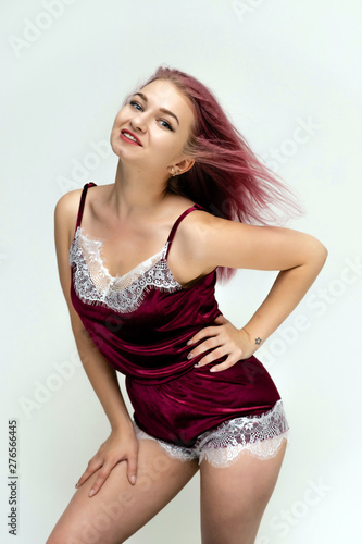 Concept portrait of a knee-high pretty sexy girl with purple hair in beautiful red lingerie on a white background. She smiles, happy with life, happy. Hair flying, front view. Made in a studio. © Вячеслав Чичаев