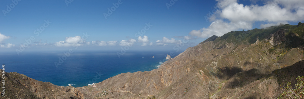 Aerial Coast view, mountain Anaga and costal village. Sunny day, clear blue sky with little fluffy white clouds. Oldest part of theTenerife. Canary Islands, Spain. Wide angle lens panorama