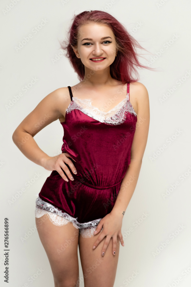 Concept portrait of a knee-high pretty sexy girl with purple hair in beautiful red lingerie on a white background. She smiles, happy with life, happy. Hair flying, front view. Made in a studio. Concept portrait of a knee-high pretty sexy girl with purple hair in beautiful red lingerie on a white background. She smiles, happy with life, happy. Hair flying, front view. Made in a studio.