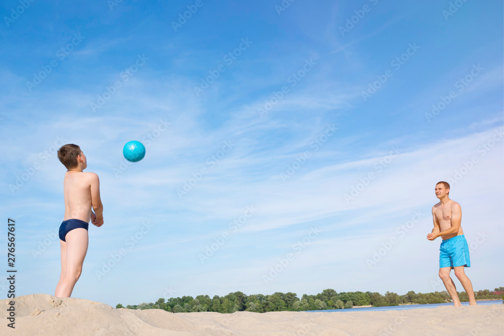 A father and a child are playing Beach Volleyball. Sports games on a sunny summer day. The concept of an active lifestyle. A father and a child are playing Beach Volleyball. Sports games on a sunny summer day. The concept of an active lifestyle.