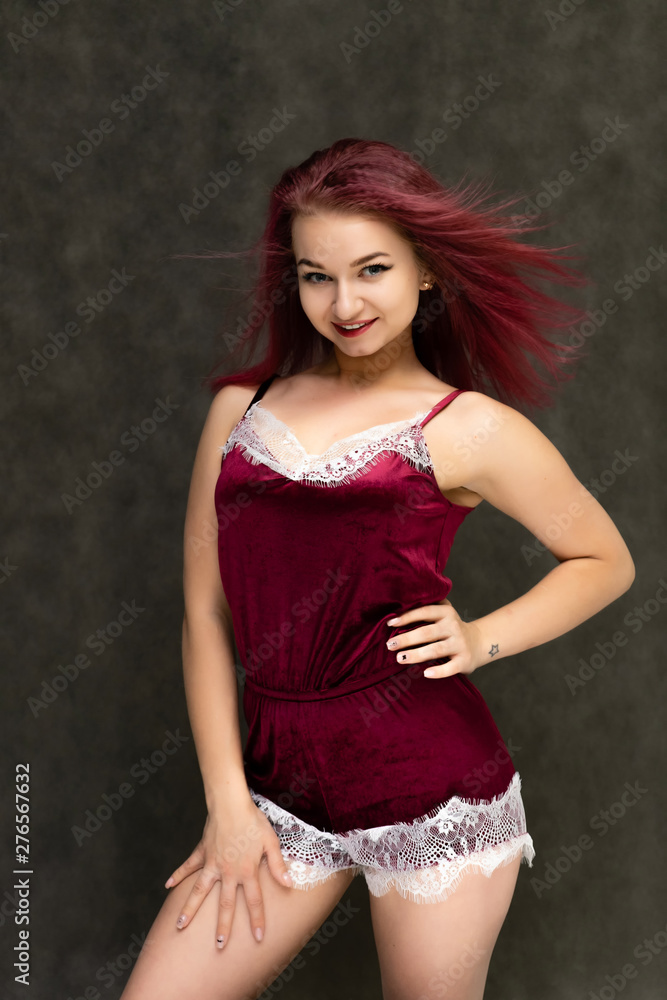 Concept portrait of a knee-high pretty sexy girl with purple hair in beautiful red lingerie on a gray background. She smiles, happy with life, happy. Hair flying, front view. Made in a studio. Concept portrait of a knee-high pretty sexy girl with purple hair in beautiful red lingerie on a gray background. She smiles, happy with life, happy. Hair flying, front view. Made in a studio.