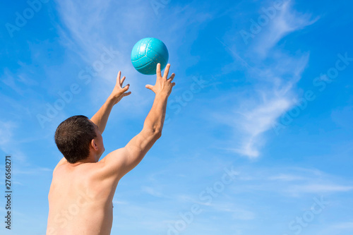A man playing beach volleyball. A back view. The concept of a healthy lifestyle.