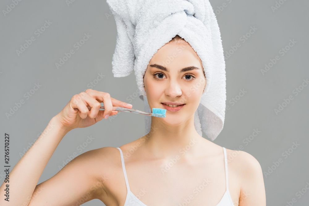 attractive young woman with towel on head holding toothbrush isolated on grey attractive young woman with towel on head holding toothbrush isolated on grey