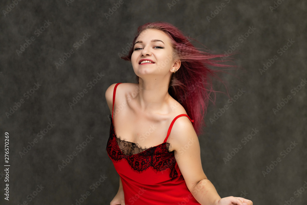 Concept portrait of a pretty sexy girl with purple hair in beautiful red lingerie on a white background. She smiles, happy with life, happy. Hair flying, front view. Made in a studio. Concept portrait of a pretty sexy girl with purple hair in beautiful red lingerie on a white background. She smiles, happy with life, happy. Hair flying, front view. Made in a studio.