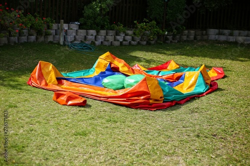 A colorful deflated jumping castle on a green lawn. This image can be used to represent the concept of a party being over or the setting up for an event.  photo