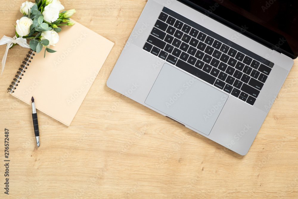 Modern wooden office desk table with laptop computer, paper notepad, pen, succulent plant, bouquet of roses flowers. Minimal flat lay style composition with copy space, top view. Feminine workspace. Modern wooden office desk table with laptop computer, paper notepad, pen, succulent plant, bouquet of roses flowers. Minimal flat lay style composition with copy space, top view. Feminine workspace.