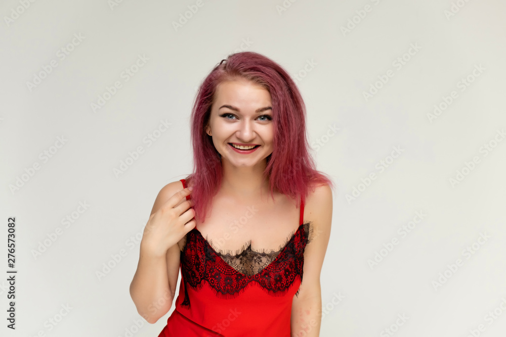 Concept portrait of a pretty sexy girl with purple hair in beautiful red lingerie on a white background. She smiles, happy with life, happy. Hair flying, front view. Made in a studio. Concept portrait of a pretty sexy girl with purple hair in beautiful red lingerie on a white background. She smiles, happy with life, happy. Hair flying, front view. Made in a studio.