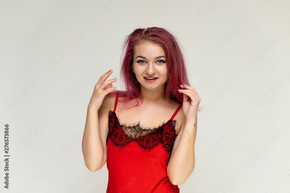 Concept portrait of a pretty sexy girl with purple hair in beautiful red lingerie on a white background. She smiles, happy with life, happy. Hair flying, front view. Made in a studio. Concept portrait of a pretty sexy girl with purple hair in beautiful red lingerie on a white background. She smiles, happy with life, happy. Hair flying, front view. Made in a studio.