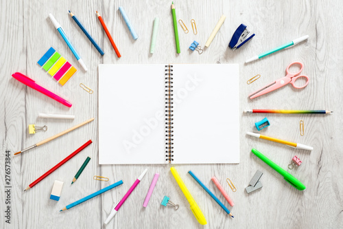 Back to school concept, creative layout with with various school supplies and blank paper notepad with copy space on wooden background. Flat lay style composition, top view, overhead. 