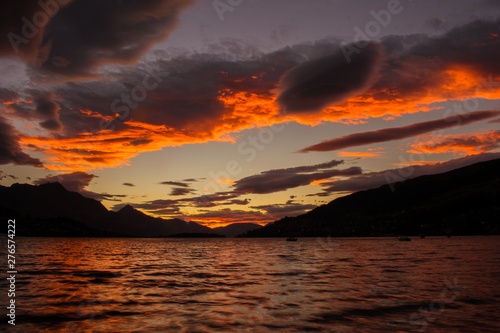 Atardecer con cielo naranja y nubes que se reflejan en el lago