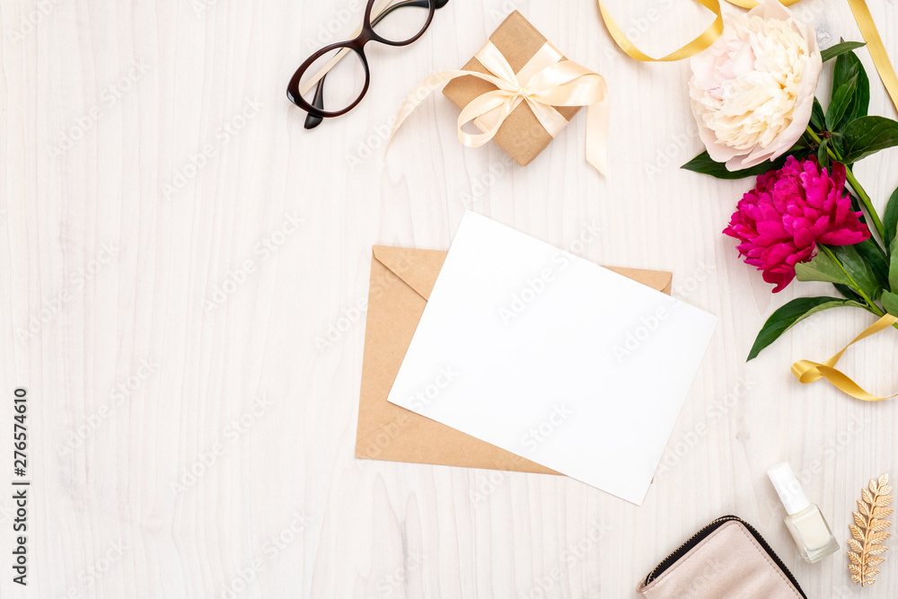 Flat lay home office desk. Female workspace with blank paper card, craft envelope, bouquet of peony flowers, golden accessories on wooden background. Top view feminine background. Fashion blog banner Flat lay home office desk. Female workspace with blank paper card, craft envelope, bouquet of peony flowers, golden accessories on wooden background. Top view feminine background. Fashion blog banner