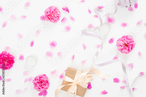 Creative wedding composition with pink rose flower buds, petals, ribbon, gift box on white background. Minimal flat lay style composition, top view. Women desk, fashion blogger, beauty concept.