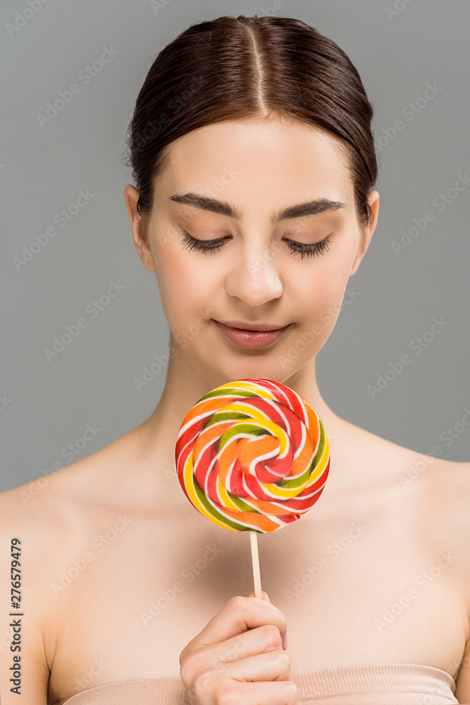 cheerful young woman holding colorful lollipop isolated on grey