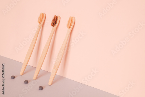 Bamboo toothbrush and dry tooth paste or toothpaste tablets on pink blue background. Zero waste, ecological concept.
