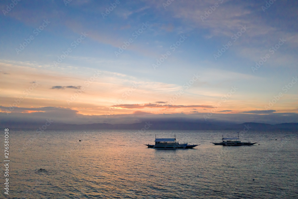 Sunset over the sea, top view. Seascape with boats. Traditional Philippine boats.