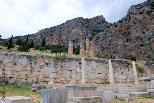 Famous polygonal wall of ancient greek city Delphi with columns of Apollo temple on the background