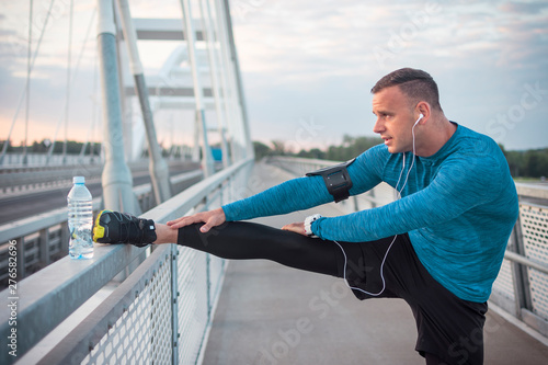 Athlete Stretching leg muscle on the bridge fence