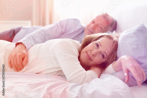 Portrait of mature couple relaxing on bed at home
