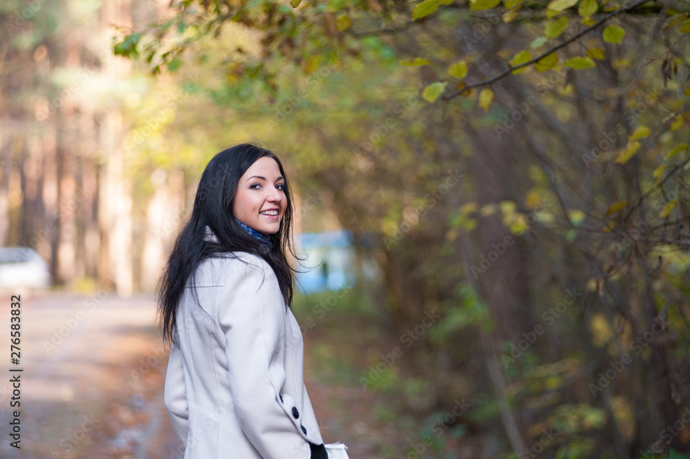 young brunette in a white jacket. Positive joyful brunette girl is relaxing outdoors in the summer. young brunette in a white jacket. Positive joyful brunette girl is relaxing outdoors in the summer.