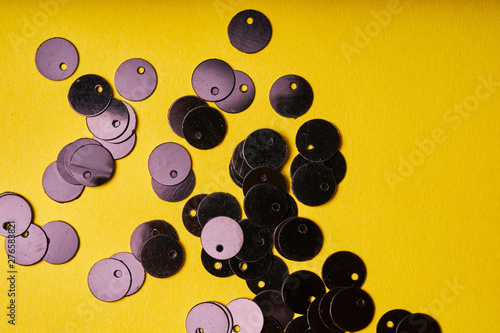 Embroidery products and tools. Black sequins on yellow background photo