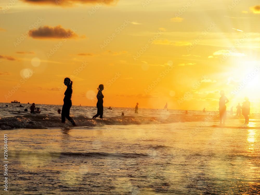 Fototapeta premium group of silhouetted people on public beach over orange colored sunset sky in Siesta key, Sarasota, Florida