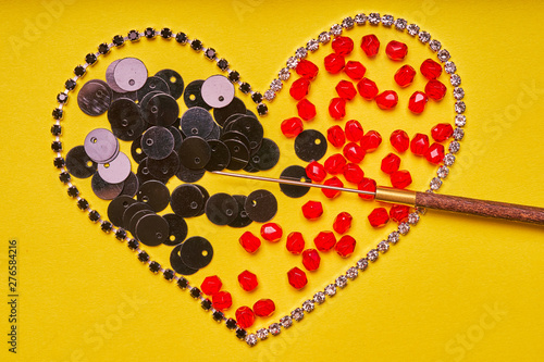 Embroidery products and tools. Heart, rhinestone, sequin and red roundels on a yellow background photo