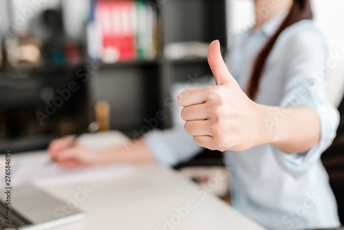 woman shows thumbs up in the office on a workplace
