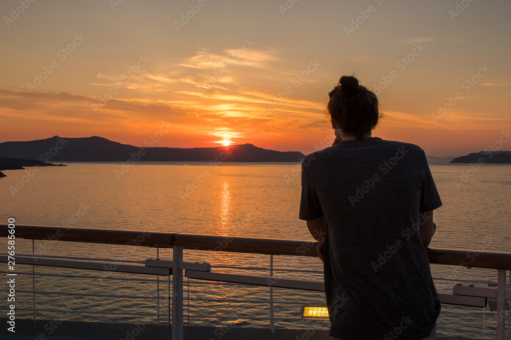 Fototapeta premium Man looking at greek costline and sea at sunset. Colorful sunset with beautiful sky