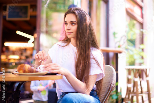 Portrait shot of young woman drinking her espresso in outdoor cafe
