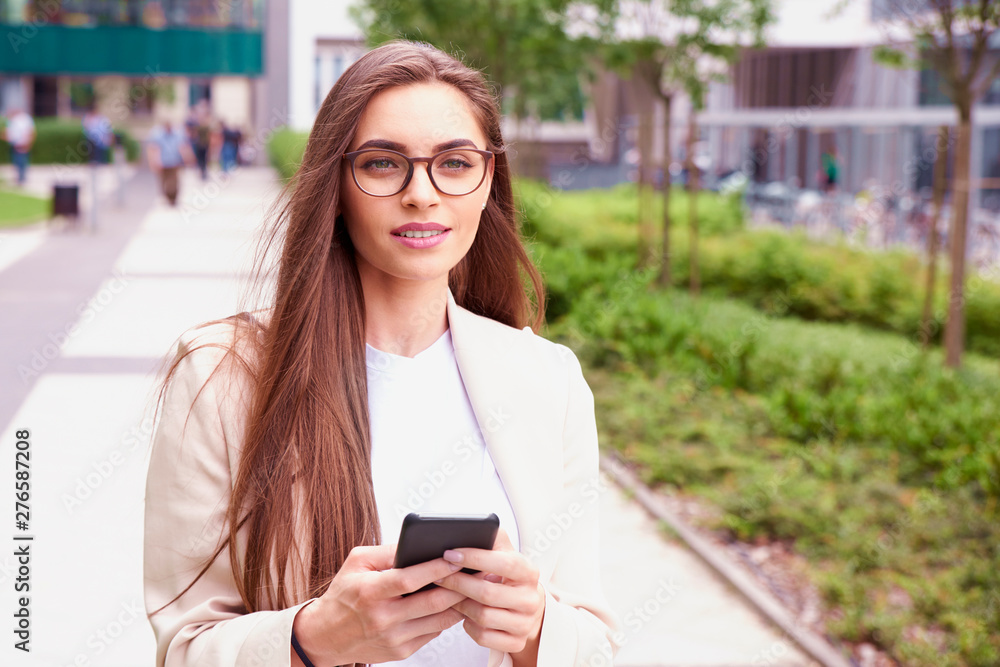 Fototapeta premium Young businesswoman give a call while walking on the street