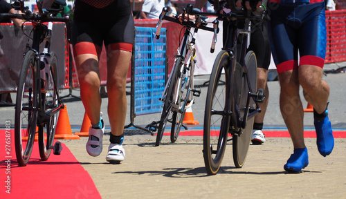 Fotografie Group of people running with bicycles to transition area after cycling in triath