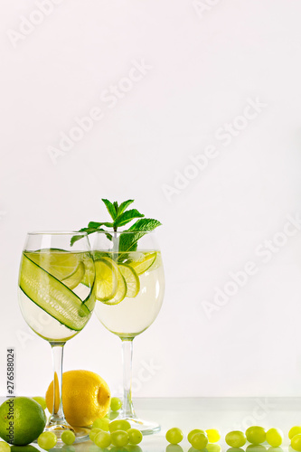 Two glasses of spritzer or lemonade with lime, cucumber, lemon and mint.