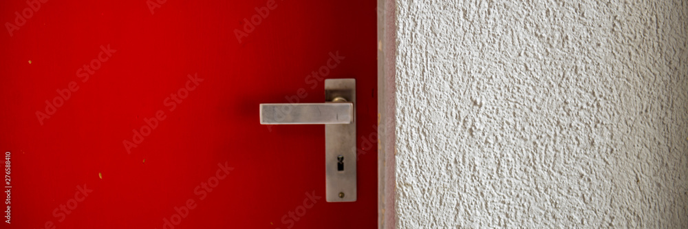 closed metal door with a handle and plastered wall.