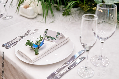 Table setting with blank guest card on empty white plate and cutlery on table  copy space. Menu mockup  place setting at wedding reception. Table served for wedding banquet in restauran