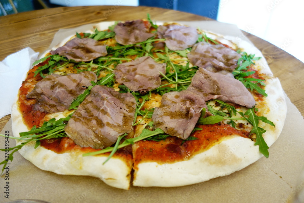 Pizza with slices of roast beef and rocket ruccola