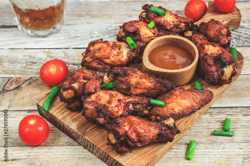 Grilled chicken wings on wooden background.