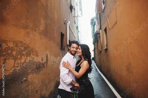 Loving couple gently leaning against each other in the old city. Behind them is the background of a terracotta wall