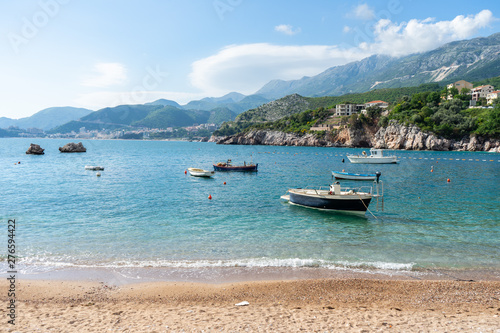 Rocks in the adriatic sea in a small coast village in Budva, Montenegro. Small boats in the beach in turquoise blue water and amazing landscape. Summer concept