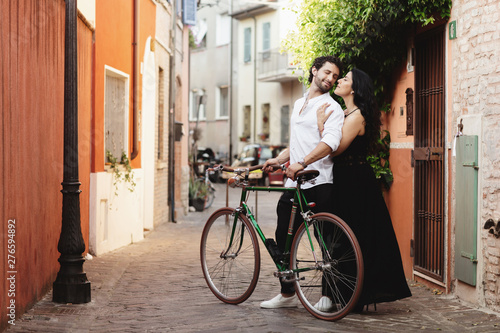 Walking a couple of lovers in the streets of the old city, with a bicycle. The woman gently hugs her man