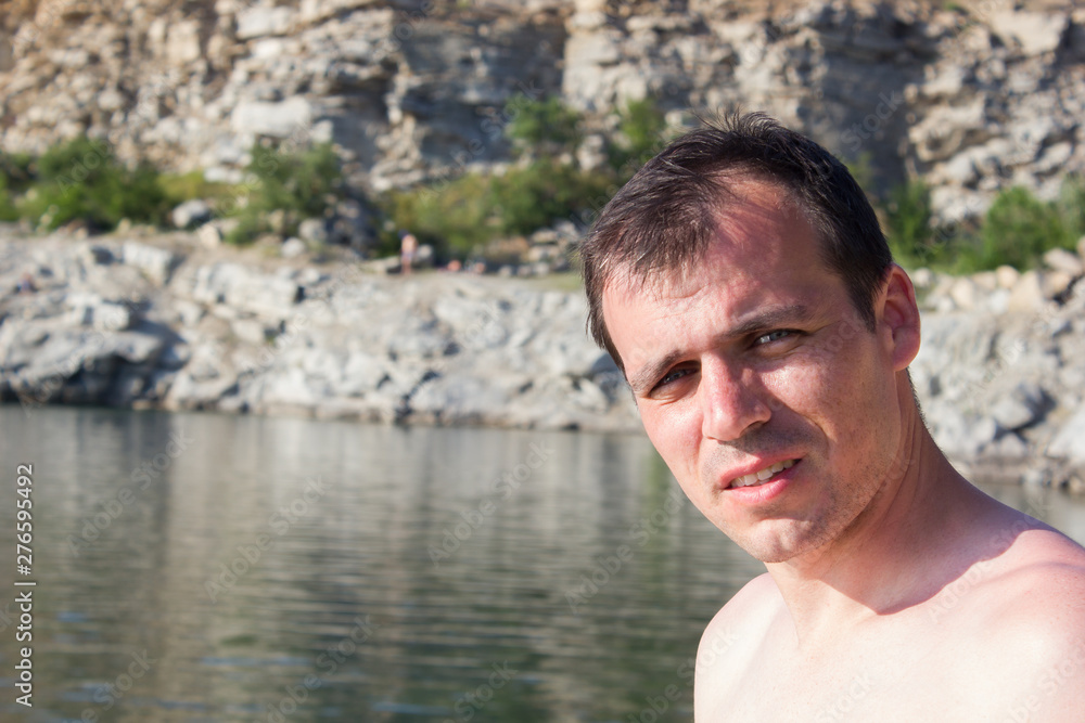 Young man on a background stones, water - summer sunny sea Young man on a background stones, water - summer sunny sea