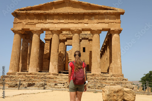 Young woman looks at Concordia Temple in the Valley of the Temples Agrigento, Sicily. Traveler girl visits Greek Temples in Southern Italy.