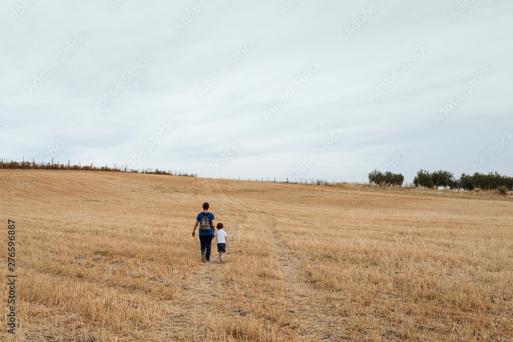 A woman and a boy walking through a field of mown wheat. A woman and a boy walking through a field of mown wheat.