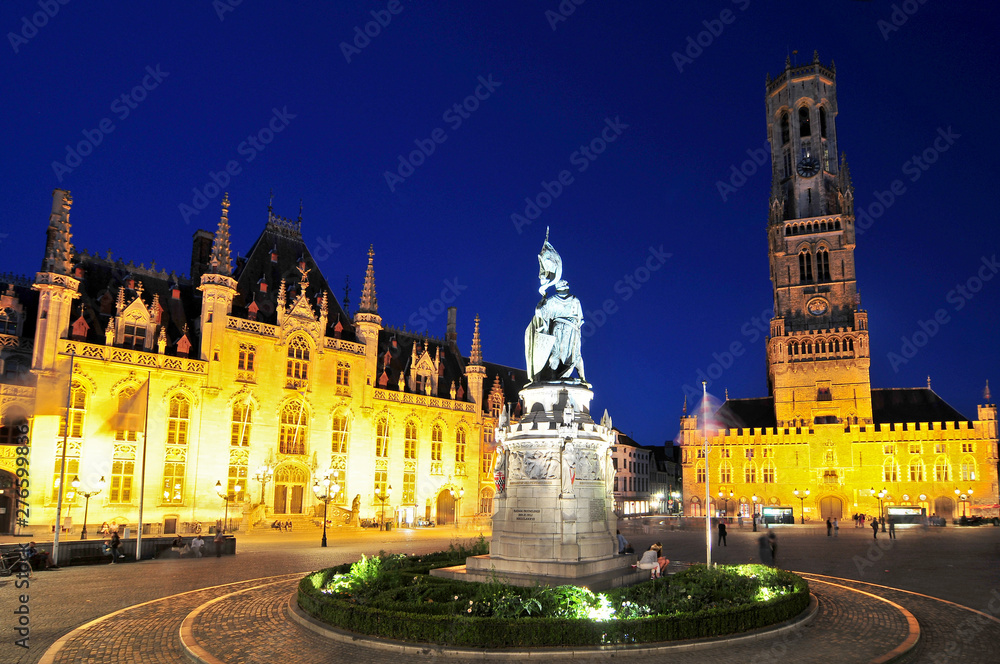 The provincial courthouse and belfry are illuminated at dusk in grote markt the city center of Brugge Belgium.