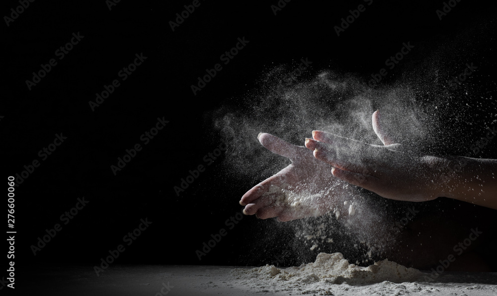 woman chef hand clap with splash of white flour and black background with copy space.